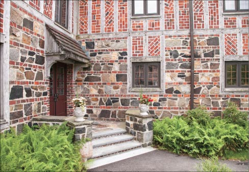 The right side entrance and corner view reveals the fine details of stone, brick and wood used in many Tudor Revival structures at the time. Built using local quarried stone and wood shipped from the west coast, the bricks are said to have come from Portland, Maine. Terracotta roof tiles, copper gutters, and down spouts conclude the charm of the “Tudor-style.”