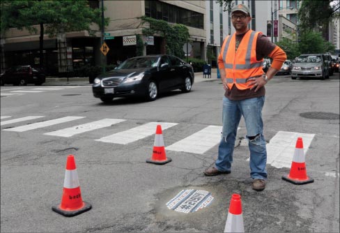 In this Tuesday, June 10, 2014 photo, mosaic artist Jim Bachor, poses next to his finished public art project on a street near downtown Chicago. Bachor has filled seven potholes around the city and marks each one with a mosaic piece. Photo: Stacy Thacker, AP