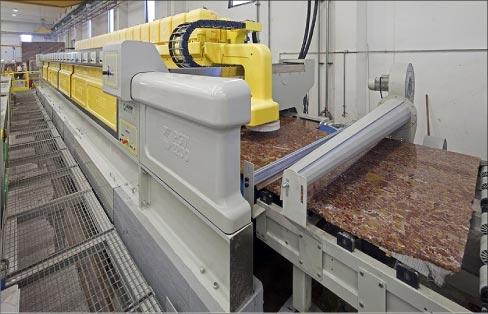 This polishing line at a slab processing plant is applying a uniform “factory finish” to slabs, prior to distribution.