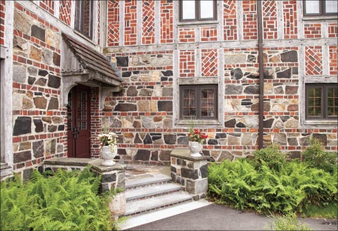 The right side entrance and corner view reveals the fine details of stone, brick and wood used in many Tudor Revival structures at the time. Built using local quarried stone and wood shipped from the west coast, the bricks are said to have come from Portland, Maine. Terracotta roof tiles, copper gutters, and down spouts add to the charm of this historic Tudor-style structure.