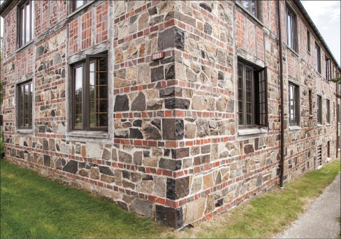 The right side entrance and corner view reveals the fine details of stone, brick and wood used in many Tudor Revival structures at the time. Built using local quarried stone and wood shipped from the west coast, the bricks are said to have come from Portland, Maine. Terracotta roof tiles, copper gutters, and down spouts add to the charm of this historic Tudor-style structure.