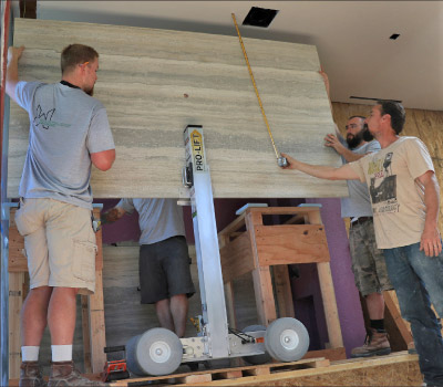 The Omni Cubed® Pro-Lift makes bringing tops onsite faster, safer and easier. Here, installers are using a Pro-lift to effortlessly hoists a shower wall panel into place.  Photo courtesy Wardlow Surfaces