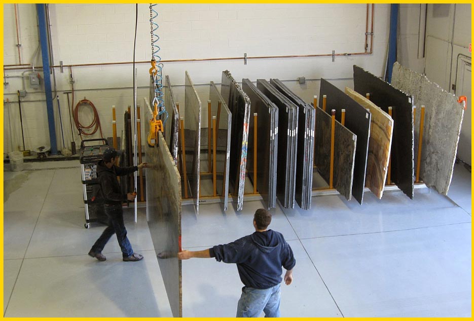 Moving a finished textured slab to a storage rack for pickup. The slabs in the rack are special orders.