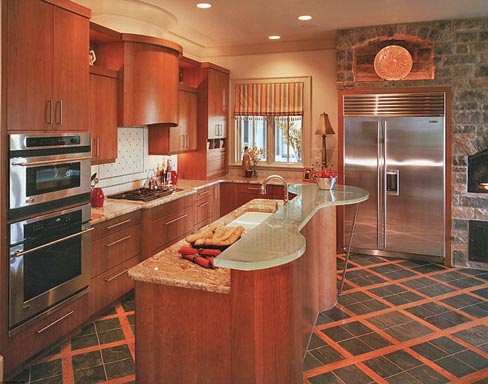 Custom kitchen produced for a country music star in 2005 includes a two-level island topped with a glass counter, curved and shaped to harmonize with the custom cabinetry and woodwork.