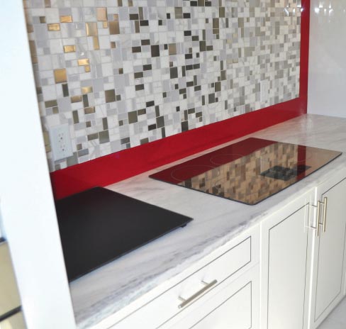 Suede Crystal White Quartzite countertops and custom island fronted by large-format white tiles. The abstract mosaic pattern is repeated on other surfaces in this Dale Woodall Custom Home.