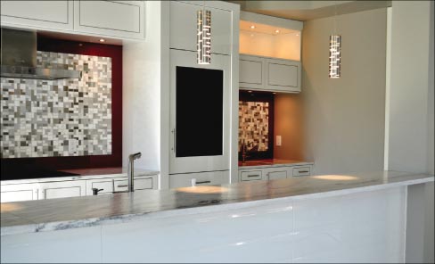 Suede Crystal White Quartzite countertops and custom island fronted by large-format white tiles. The abstract mosaic pattern is repeated on other surfaces in this Dale Woodall Custom Home.