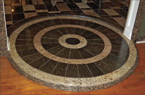 Granite medallion steps with radial Black Galaxy tiles leads from the dining room to the living room.