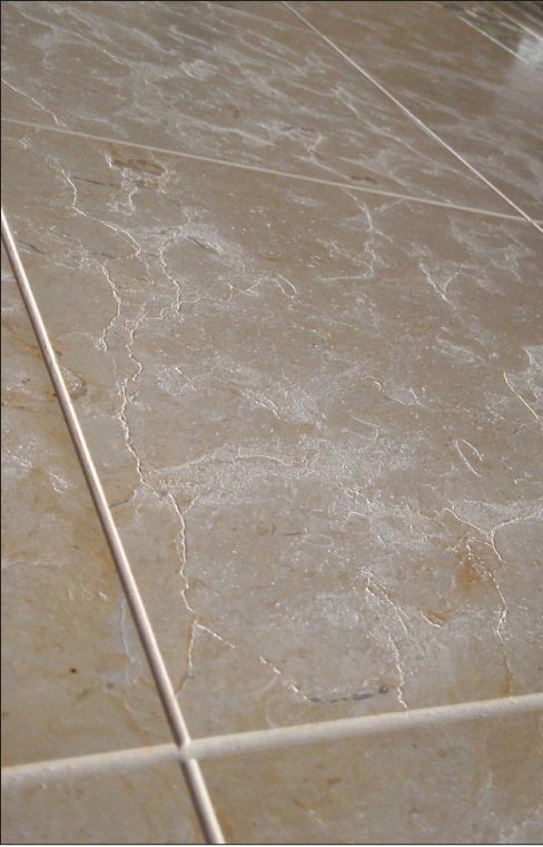 The white residue is efflorescence damage in sealed tile. Moisture is still trapped under a sealer, which is blocking evaporation.