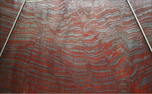 In this Iron Red slab, the stripes of intense red and sparkly grey are accumulations of iron oxide and sand sediment that accumulated  only during a specific era in the earth’s geologic history.