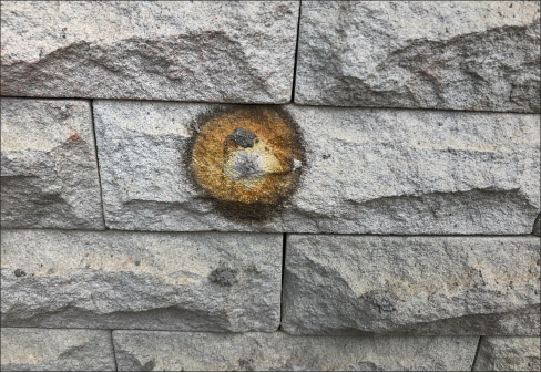 These odd orange blossoms of stain show the presence of iron oxidation. Iron is naturally present in many stones, including limestone, like this exterior façade. 