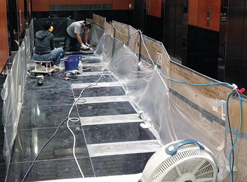 Boua and Jaron Wiley resurfacing, honing and polishing black galaxy granite tiles at the Fox Tower Building in Portland.