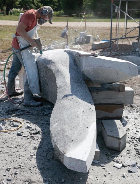 Mathew Foster of Maine, representing Bucksport, Maine, is hard at work bush hammering his latest large-scale work. All sculptures are created using cubic material quarried from sources within Maine. “I think that’s probably the neatest things about this particular symposium is that we have Miles Chapin and Mathew Foster. Both are artists that worked with us in prior symposiums as assistants and have now progressed in their own right as full artists. So watching them making these big monumental pieces is amazing and a highlight in their career,” explained Executive Managing Director, Tilan Copson.