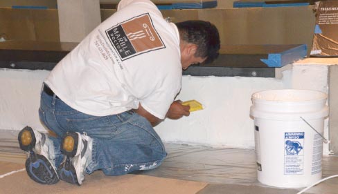 Technician Jose Perez applies a coat of 24-hour latex poultice to a wall opposite the barracks from the Auschwitz exhibit. The latex poultice was a key material used during the restoration because of its ability to be removed quickly, allowing the museum to remain open while The Marble Doctor team worked their magic.